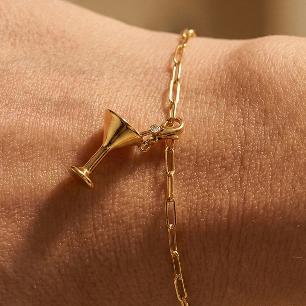 Der Cocktail Charm in gold an einem goldenen Paperclip Armband um ein weibliches Handgelenk