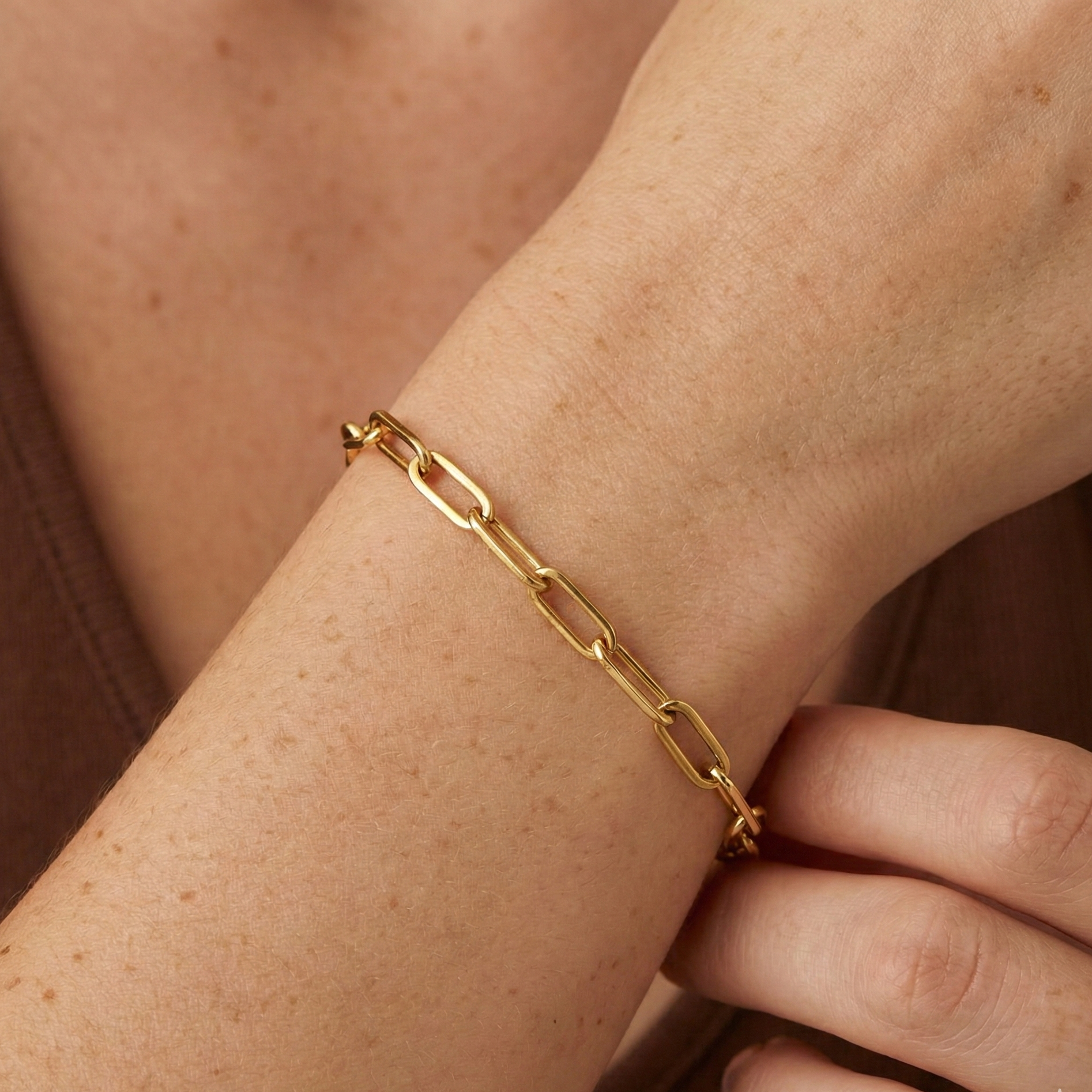 Nahaufnahme eines goldenen Paperclip Armbands an Handgelenk