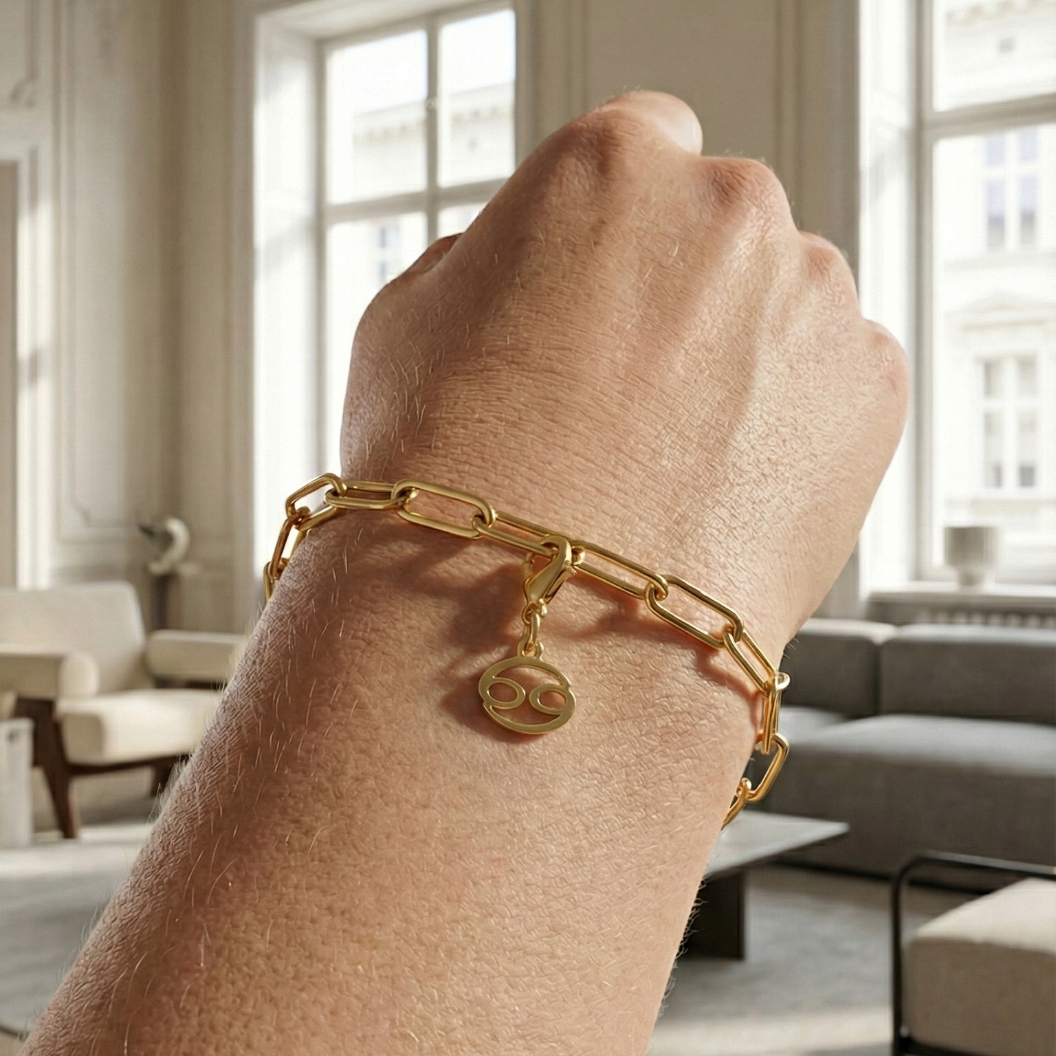 Charm Sternzeichen Krebs in gold hängt an goldenem Armband am Handgelenk. Im Hintergrund stylische Altbauwohnung