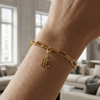 Charm Sternzeichen Skorpion in gold hängt an goldenem Armband am Handgelenk. Im Hintergrund stylische Altbauwohnung