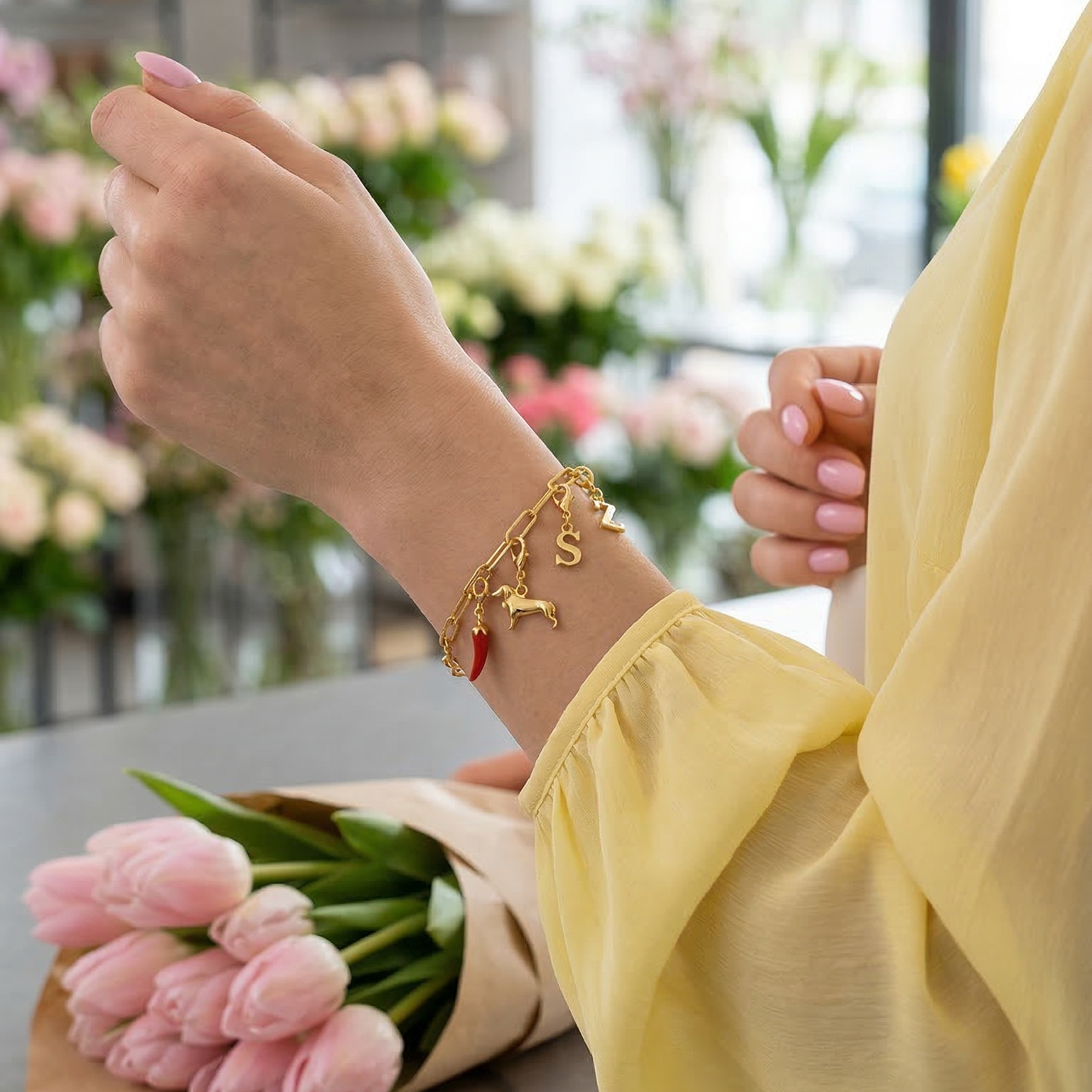 Goldenes Armband mit Charms am Handgelenk im Blumengeschäft