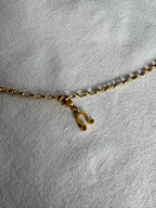 Goldener Löwe Sternzeichen Charm an  goldenem Armband liegt auf weißem Leinentuch