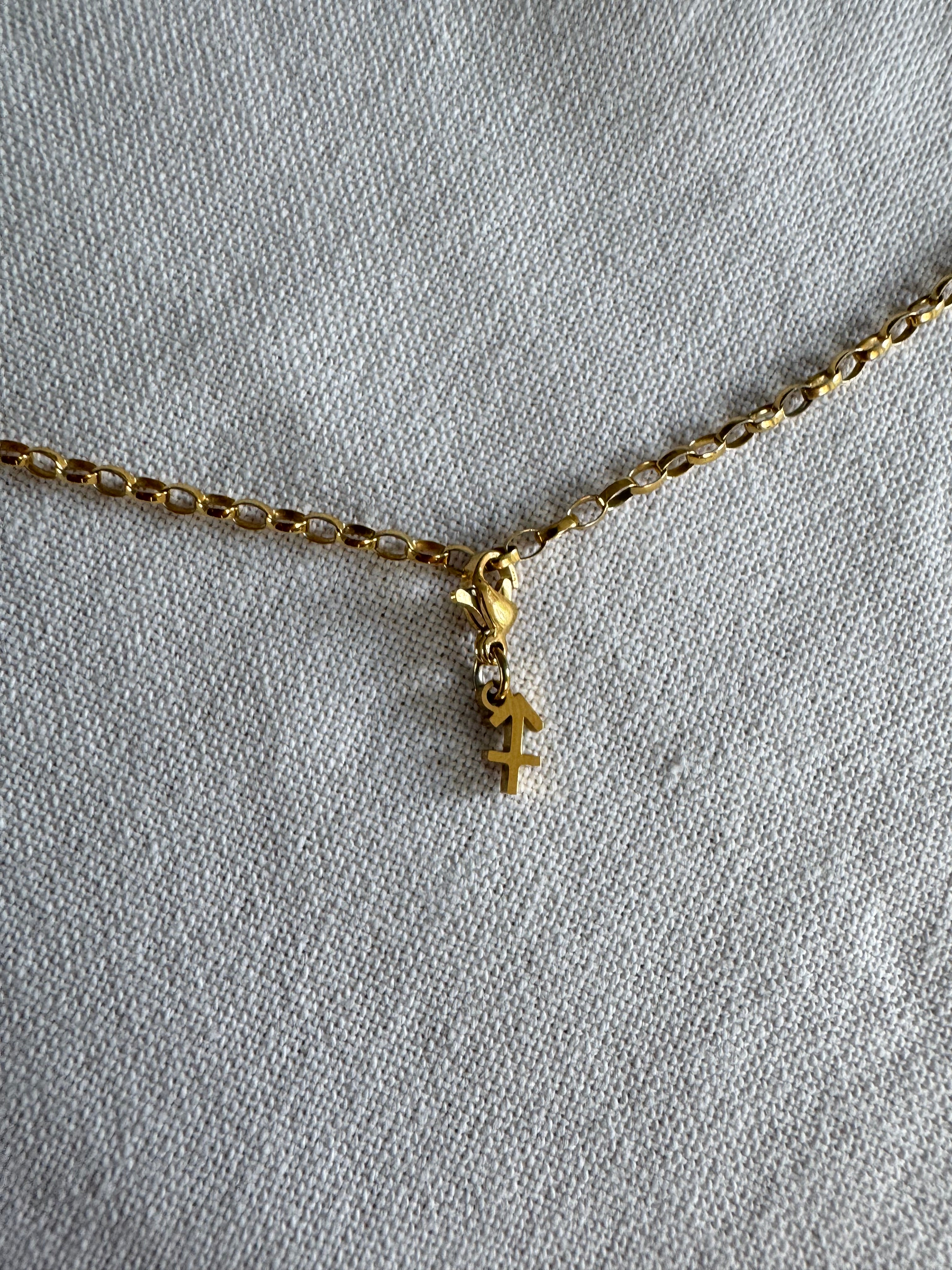 Goldener Schütze Sternzeichen Charm an  goldenem Armband liegt auf weißem Leinentuch