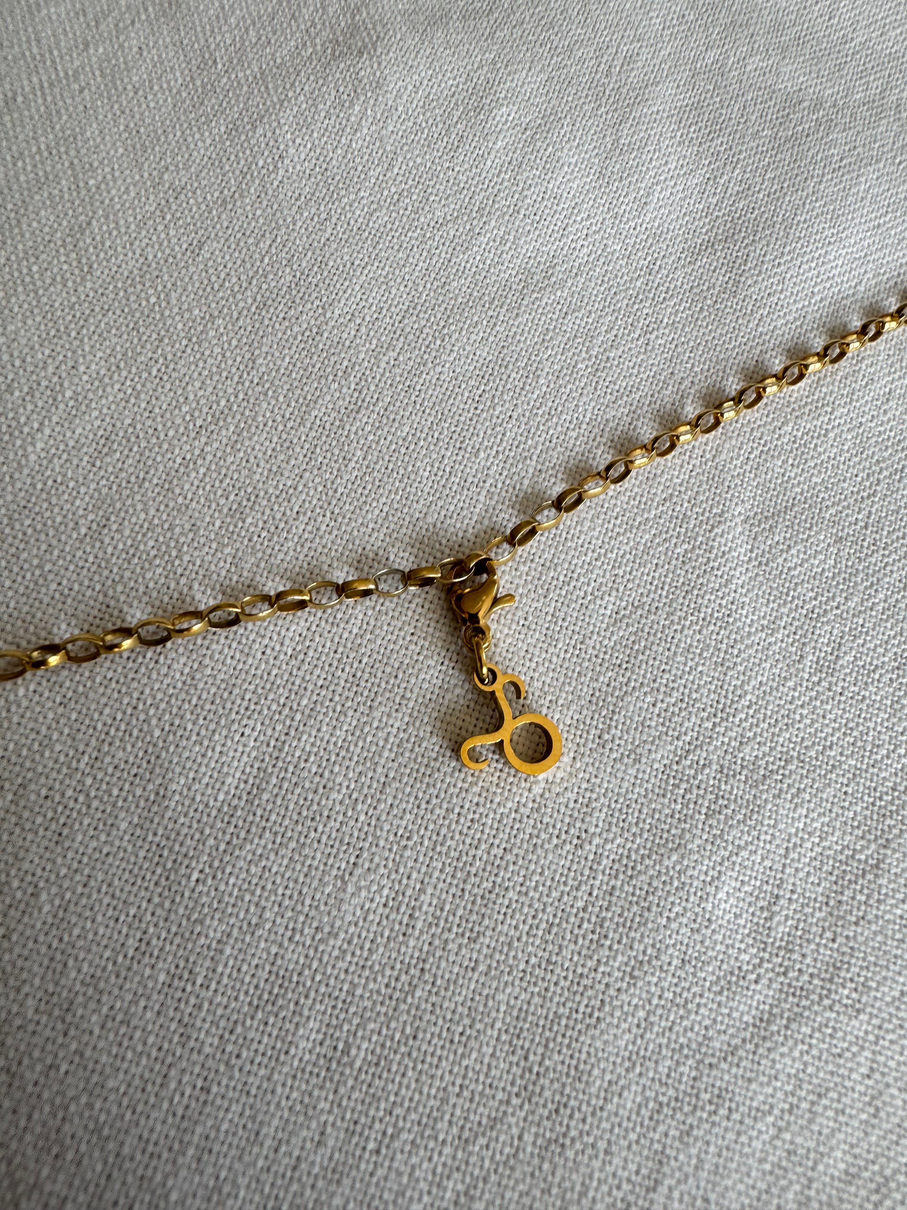 Goldener Stier Sternzeichen Charm an  goldenem Armband liegt auf weißem Leinentuch