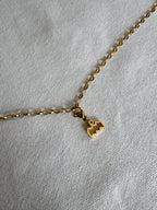 Goldener Wassermann Sternzeichen Charm an  goldenem Armband liegt auf weißem Leinentuch