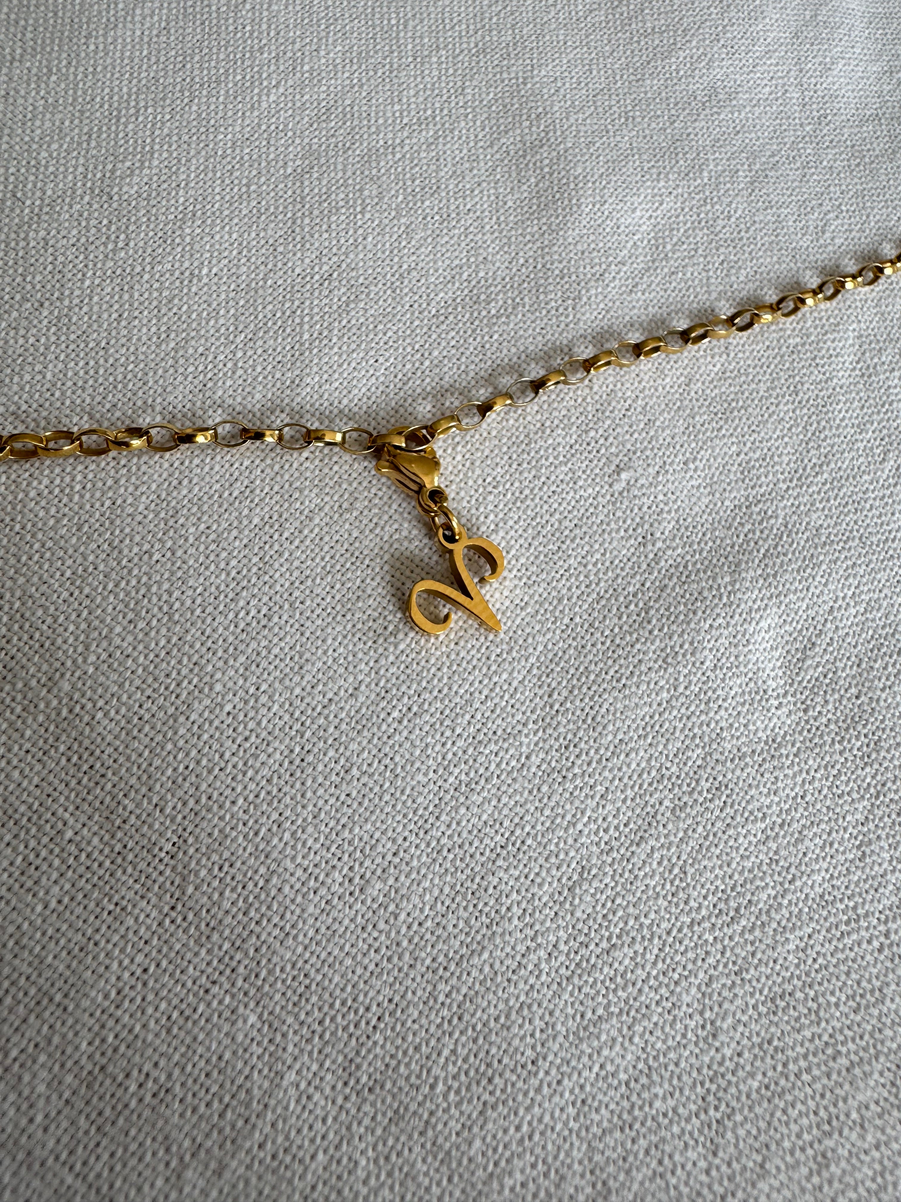 Goldener Widder Sternzeichen Charm an  goldenem Armband liegt auf weißem Leinentuch
