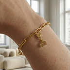 Charm Sternzeichen Wassermann in gold hängt an goldenem Armband am Handgelenk. Im Hintergrund stylische Altbauwohnung