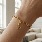 Charm Sternzeichen Widder in gold hängt an goldenem Armband am Handgelenk. Im Hintergrund stylische Altbauwohnung